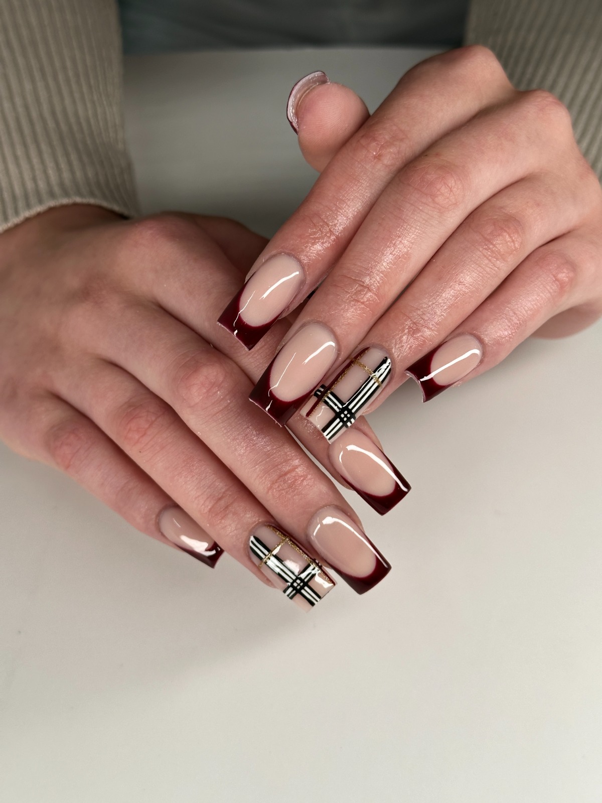 Nude Nägel mit bordeauxroten French-Spitzen und Karo-Akzentnagel